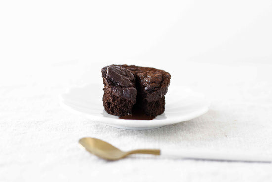 A white plate of Mini Chocolate Lava Cakes placed on a white covered surface.