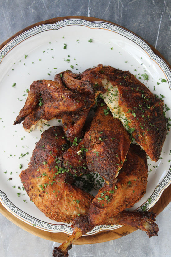 A plate of beer butt chicken placed on a grey surface.