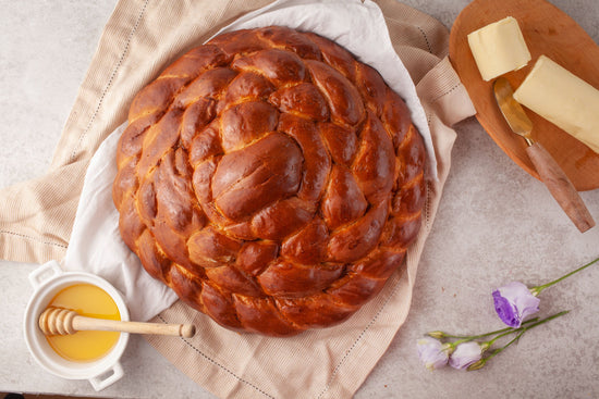 Crowd-pleasing Challah bread with a bowl of honey on a marble surface.