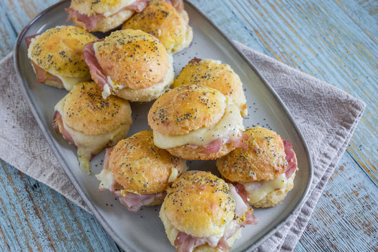A tray of ham and cheese sliders on a blue surface.