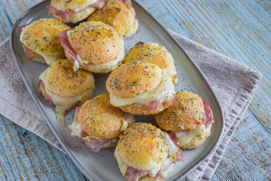 A tray of ham and cheese sliders on a blue surface.