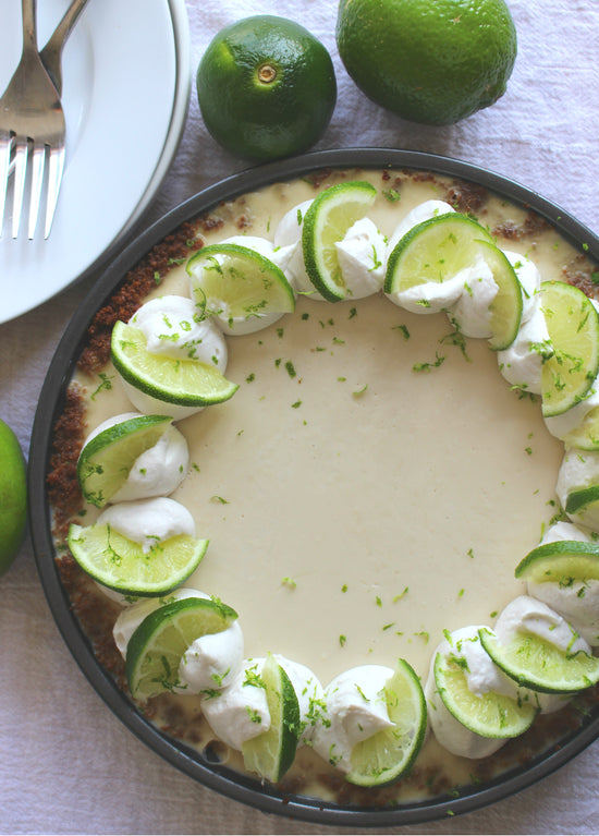 A plate of keylime pie placed next to some limes. 