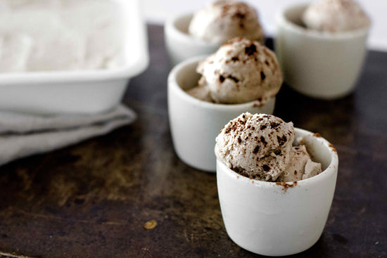 Mugs of Chai Ice Cream on a brown surface.
