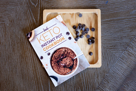 Keto instant pot cookbook on a squared wooden plate with chocolate chips.
