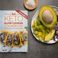 Keto Slow Cooker Cookbook Volume 2  laid on a grey surface next to a plate of avocados and onions. A bowl of sea salt is also visible.