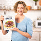 The cookbook author Kelsey Ale stands in the kitchen, holding the Keto Baker recipe book.