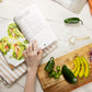 An opened Thyroid Rebook book on a kitchen cloth placed on a marble surface next to a wooden board with sliced vegetables. Measuring spoon, and some vegetables and also be seen.