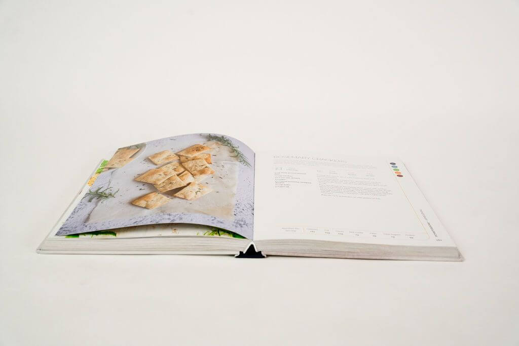 Opened Keto Baker cookbook placed on a white surface.